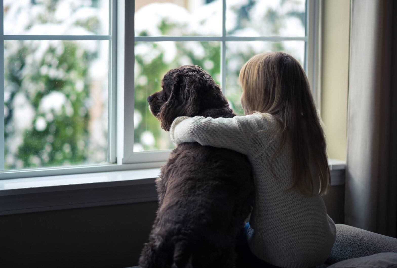 Little girl and her dog looking out the window.